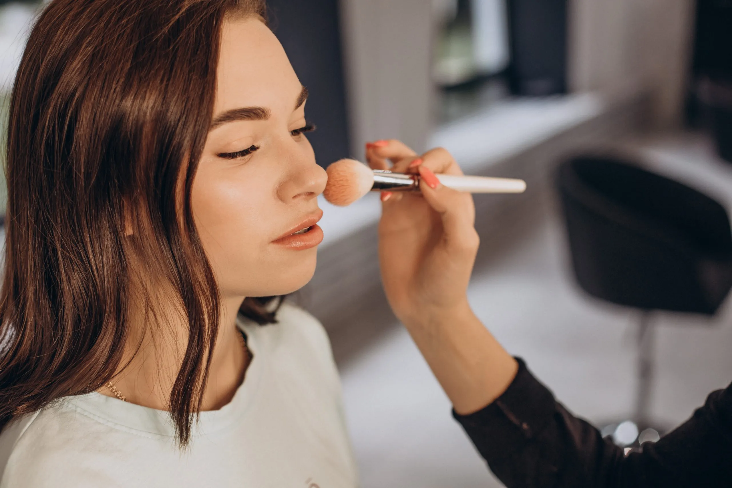 Visagistin trägt professionelles Make-up bei einer Kundin auf